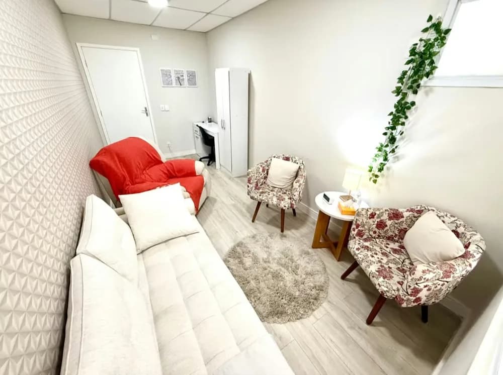 Sala de atendimento acolhedora com sofá, poltronas e planta